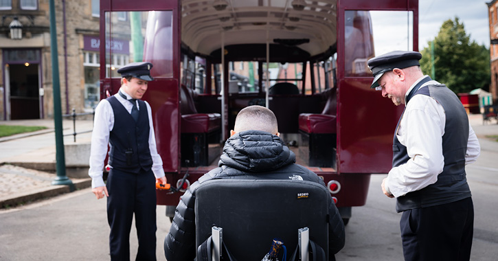A wheelchair user is helped onto the accessible transport by two members of staff at Beamish Museum.